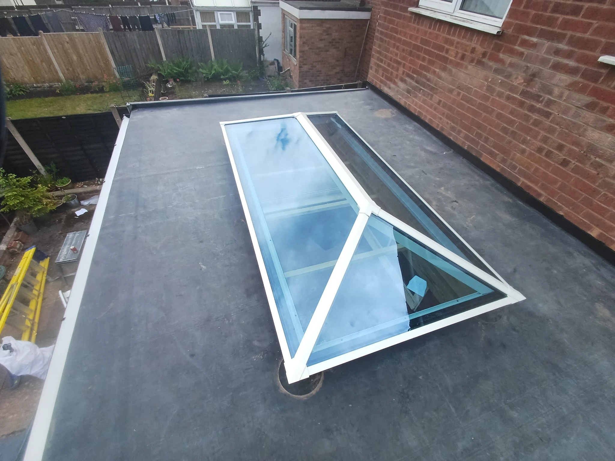 Flat roof with a white-framed glass skylight window on a residential building.
